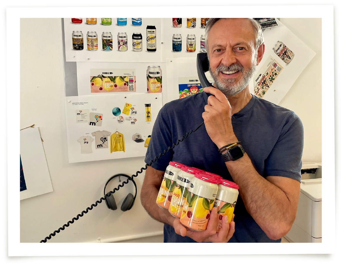 Len on the phone holding the new Pink Lemonade Lager can design for Marble Brewery